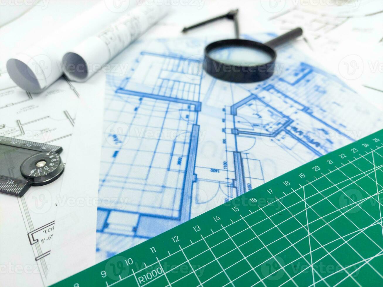 Architect rolls, compass, magnifier glass and house plans, close up. Side view photo