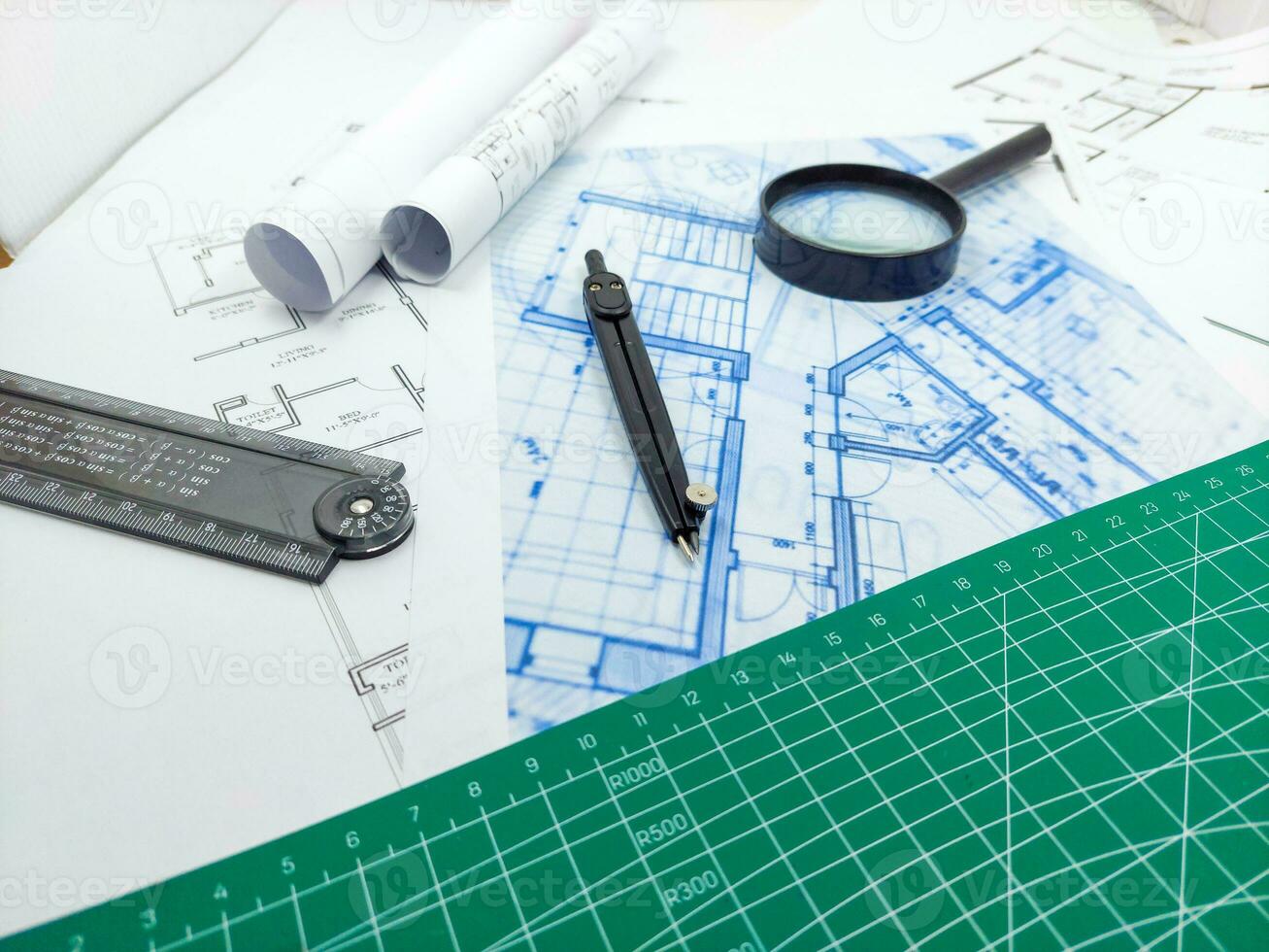 Architect rolls, compass, magnifier glass and house plans, close up. Side view photo