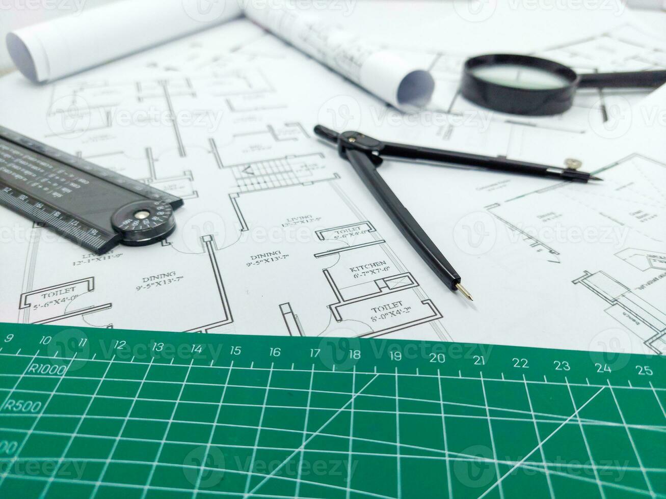 Architect rolls, compass, magnifier glass and house plans, close up. Side view photo