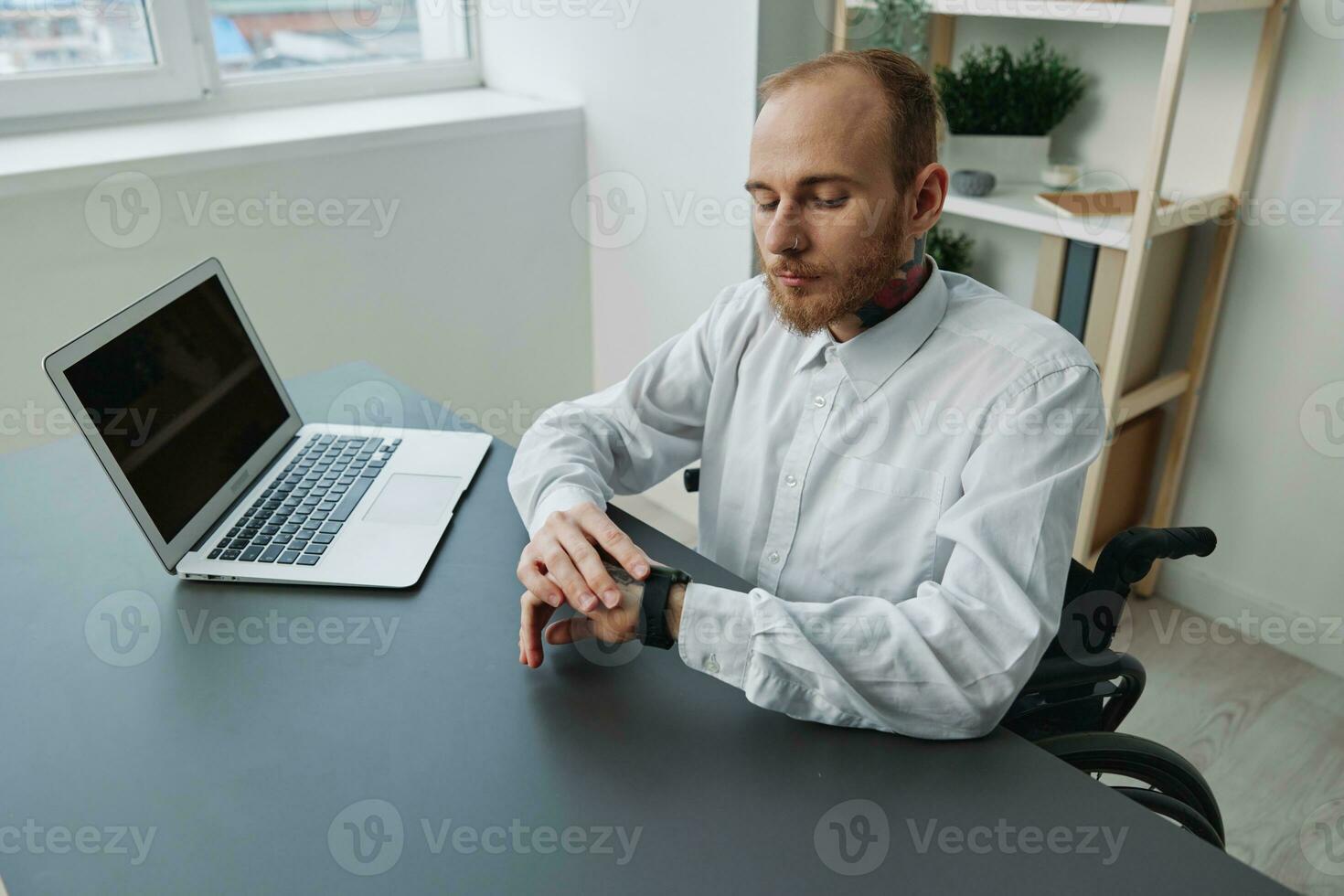 A man wheelchair, a businessman in an office at a laptop, fatigue and emotional burnout at the end of the working day, the concept of working a person with disabilities, freedom from social frameworks photo