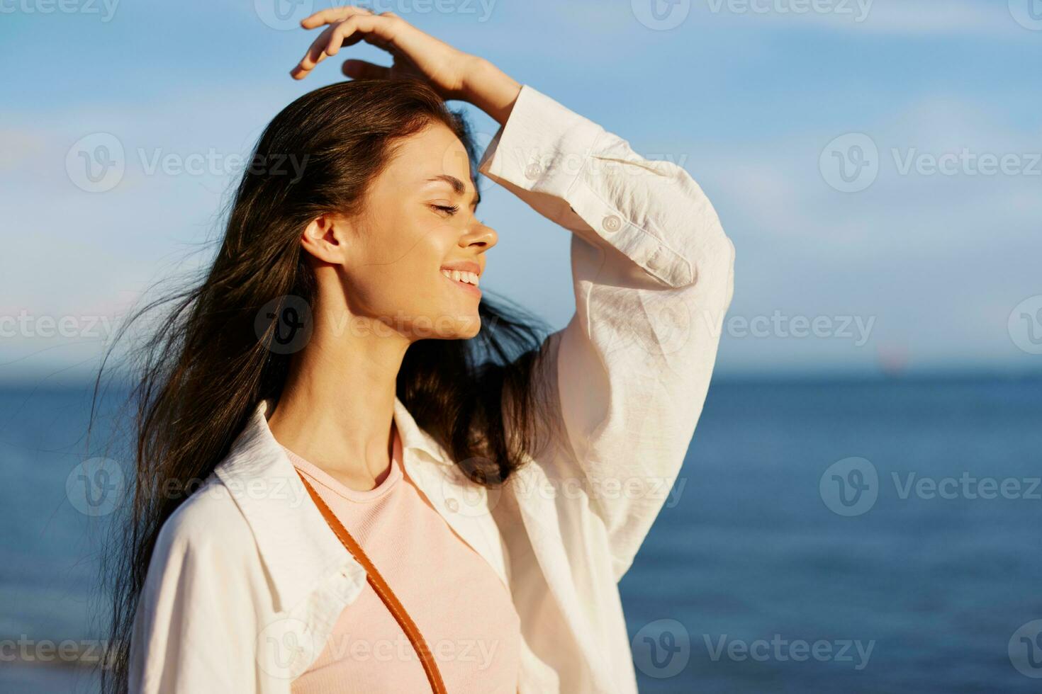 Woman portrait smile with teeth freedom on vacation walking on the beach by the ocean in Bali sunset, happy travel and vacation, sunset light, flying hair, skin and hair care concept in the sun photo