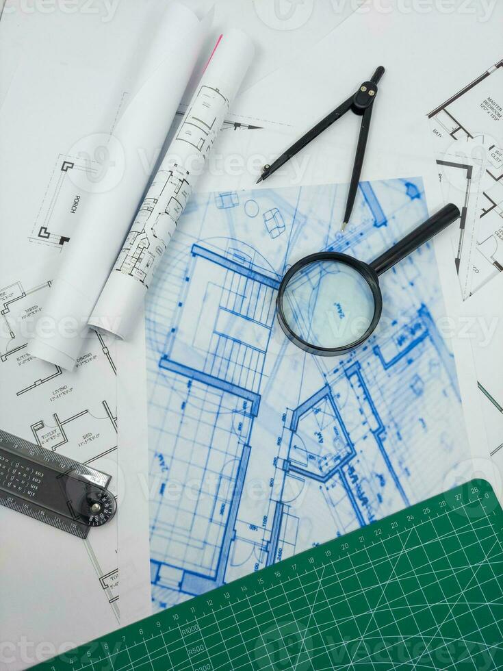 Architect engineer office desk. Blueprint plans and house model with ruler, compass, and magnifier glass photo