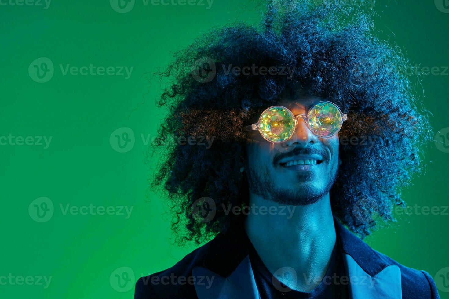 Moda retrato de un hombre con Rizado pelo en un verde antecedentes con Gafas de sol, multinacional, de colores rosado luz, de moda, moderno concepto. foto