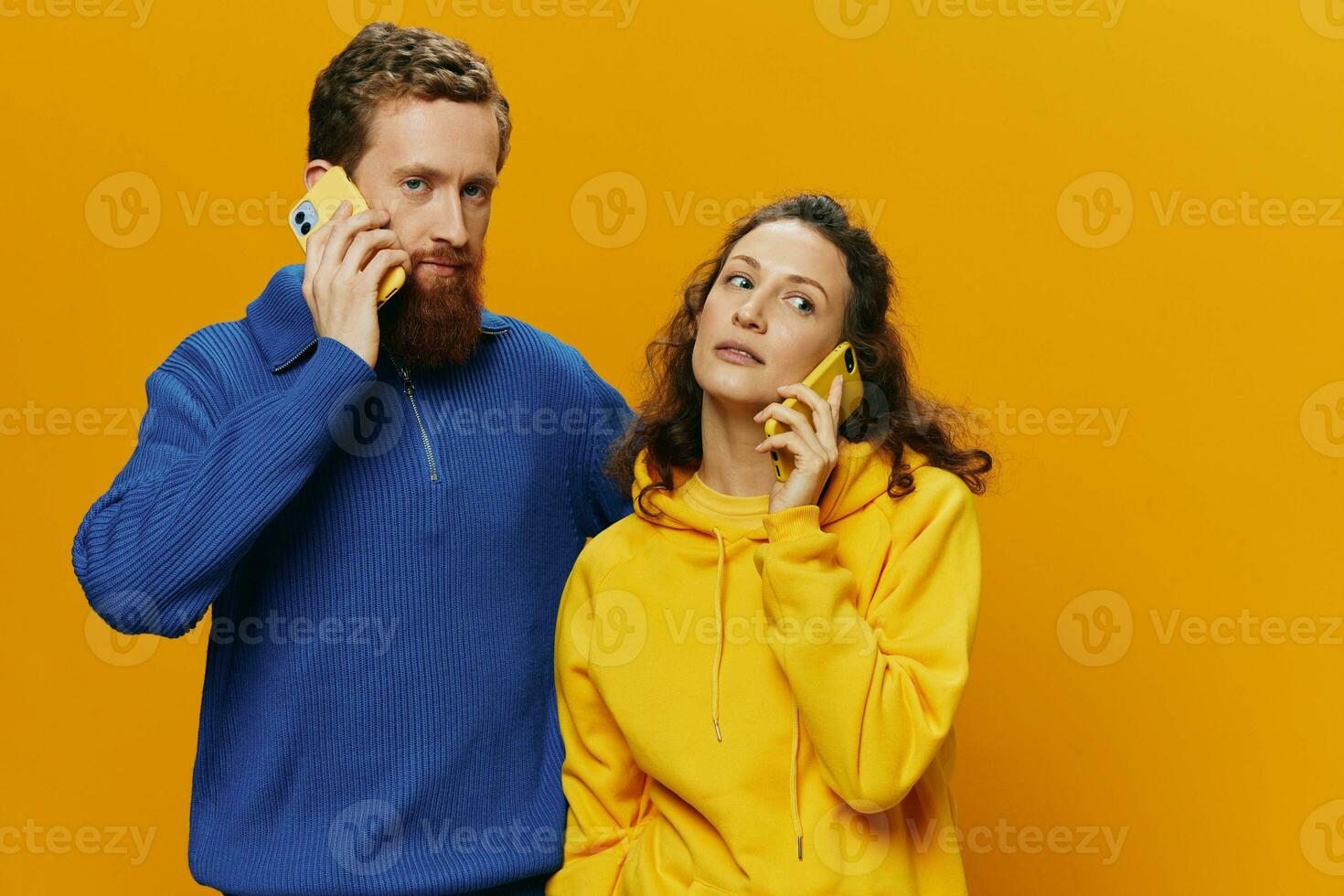 Man and woman couple smiling merrily with phone in hand social media viewing photos and videos, on yellow background, symbols signs and hand gestures, family freelancers.
