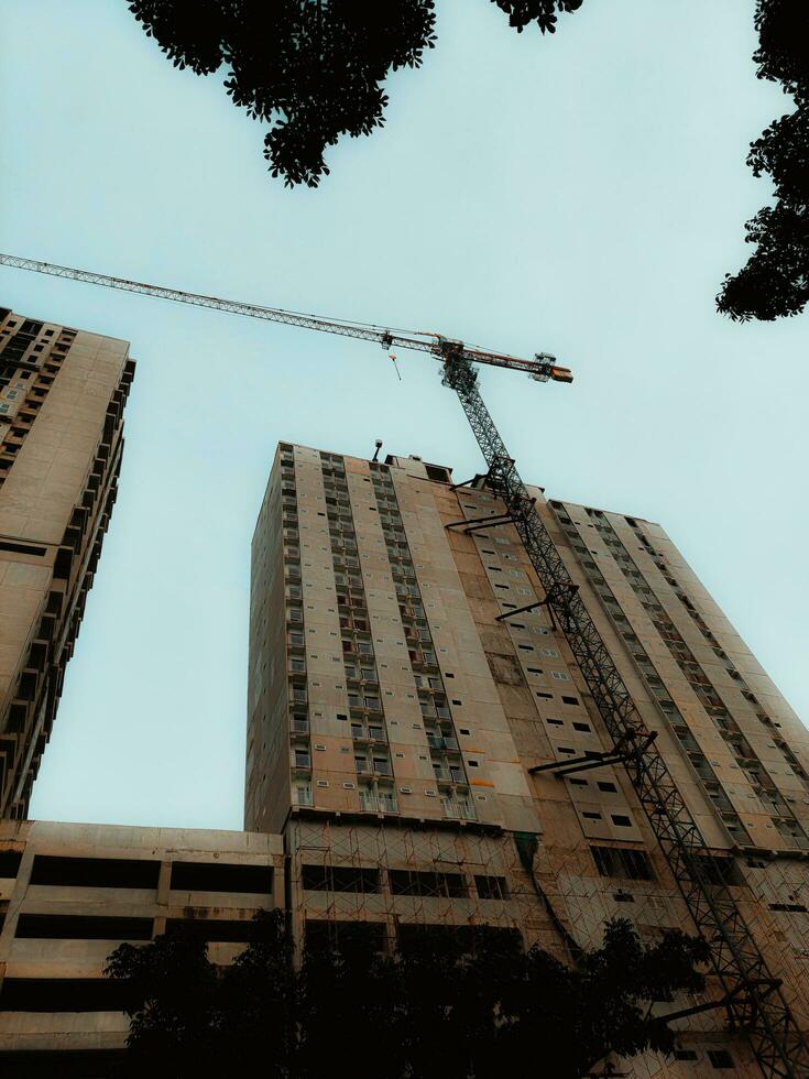 unfinished building construction and building cranes against clear blue sky background photo