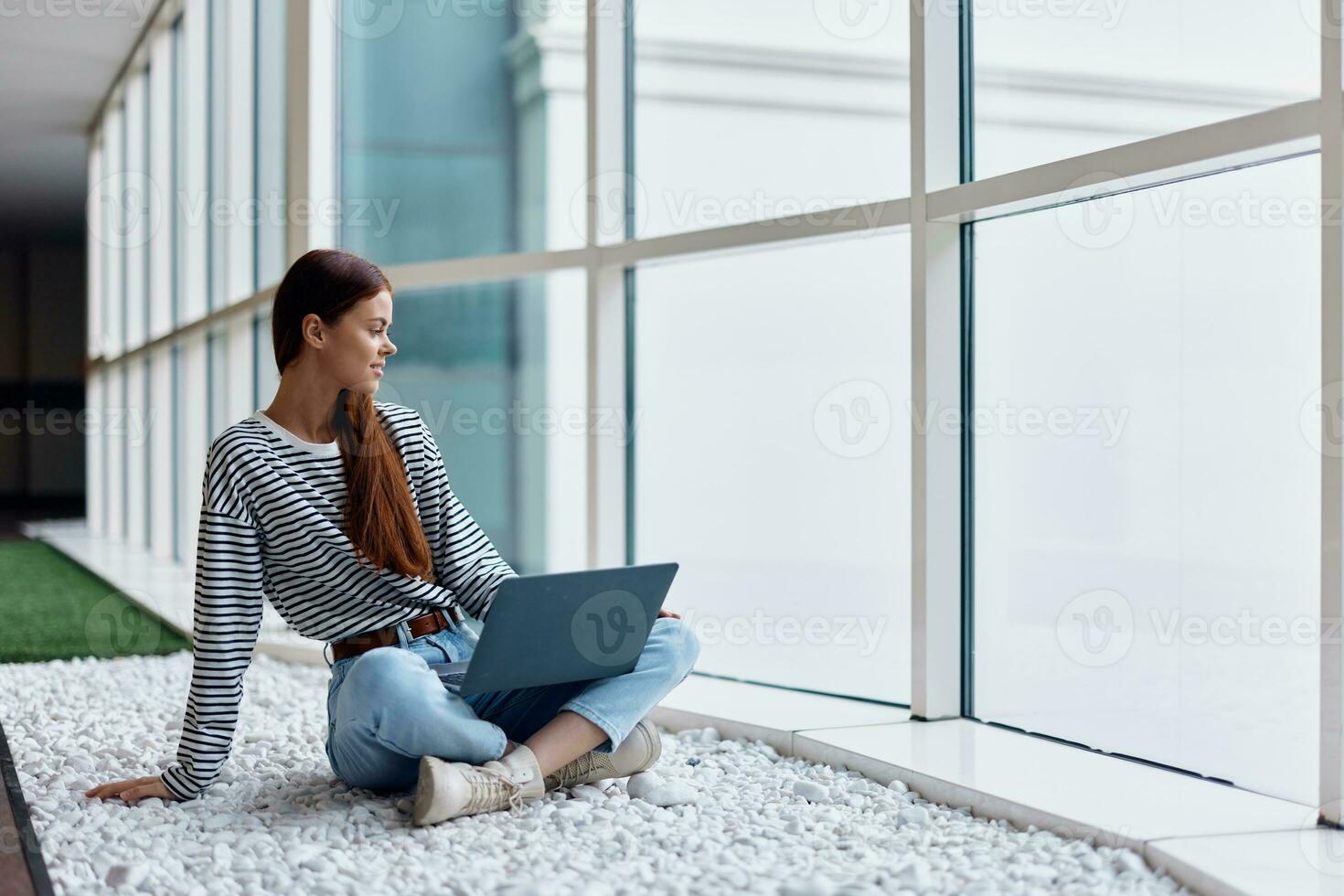A woman freelancer sits with her laptop near a window overlooking the city and works online via the Internet, an online shopping concept, a copying place photo