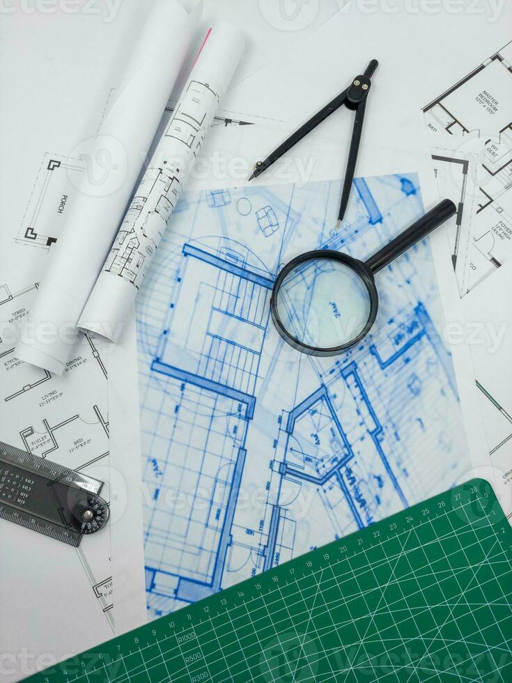 Architect engineer office desk. Blueprint plans and house model with ruler, compass, and magnifier glass photo