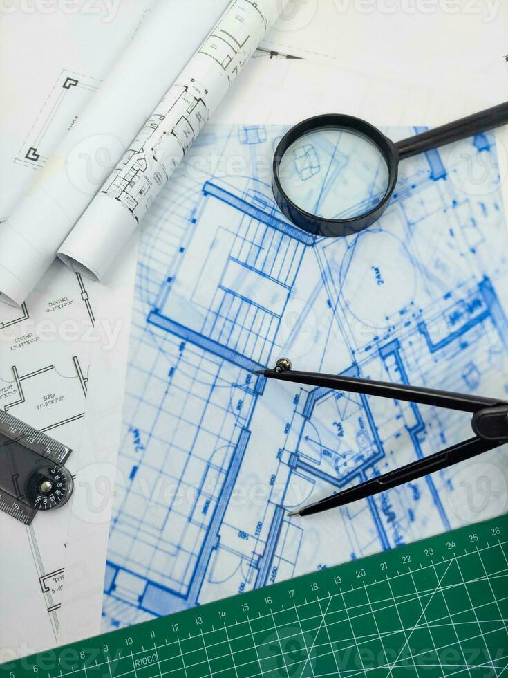 Architect engineer office desk. Blueprint plans and house model with ruler, compass, and magnifier glass photo