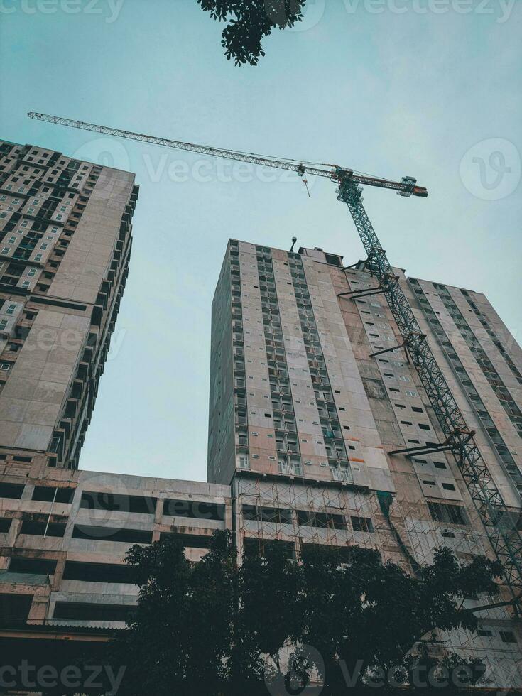 unfinished building construction and building cranes against clear blue sky background photo