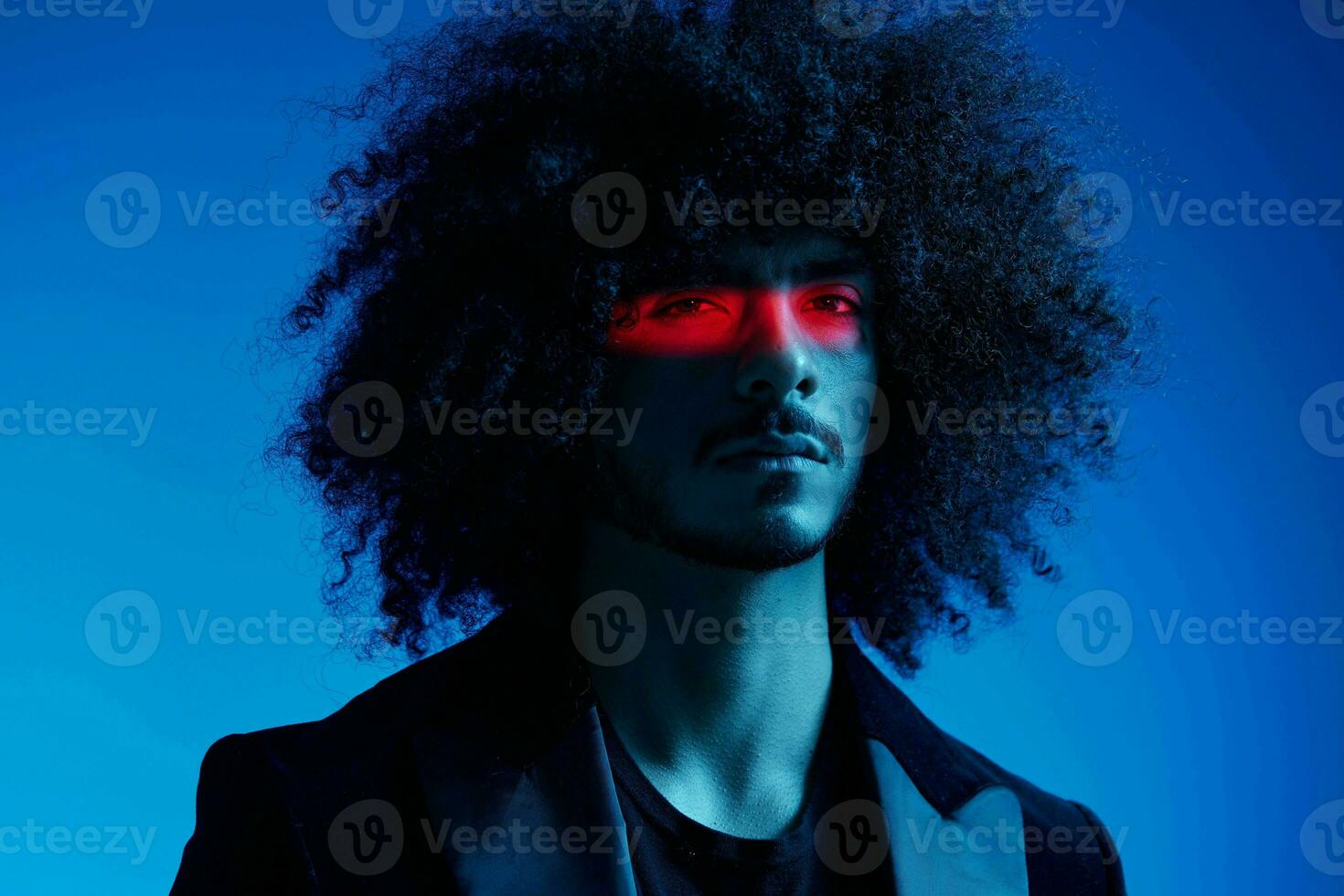 Fashion portrait of a man with curly hair on a blue background with a red stripe of light, multicolored light, trendy, modern concept. photo