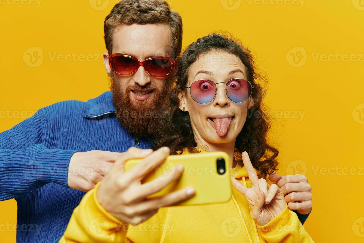 Woman and man funny couple with phones hand social networking and communication crooked do selfies smile fun, on yellow background. The concept of real family relationships, freelancers, work online. photo