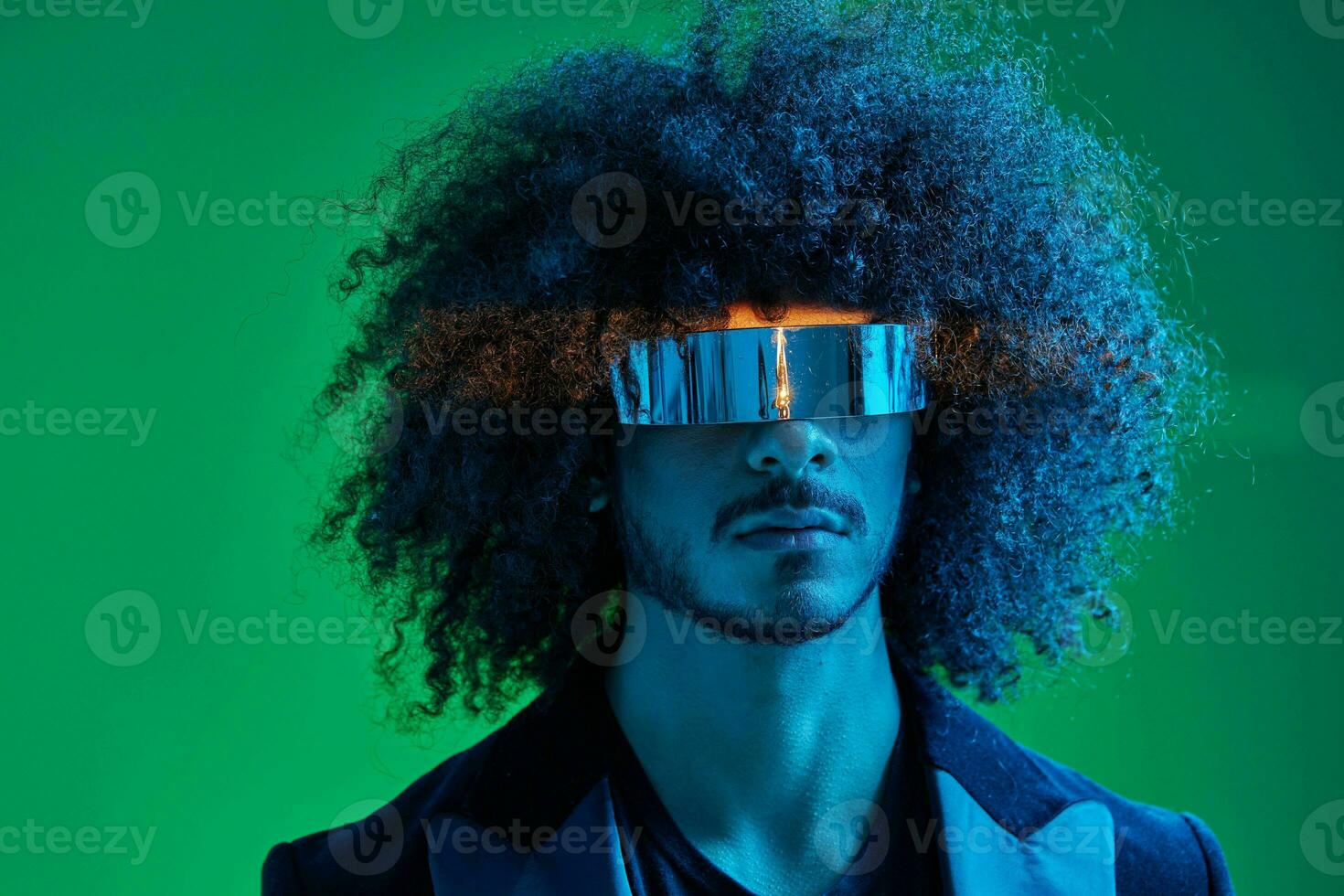 Fashion portrait of a man with curly hair on a green background with sunglasses, multinational, colored pink light, trendy, modern concept. photo