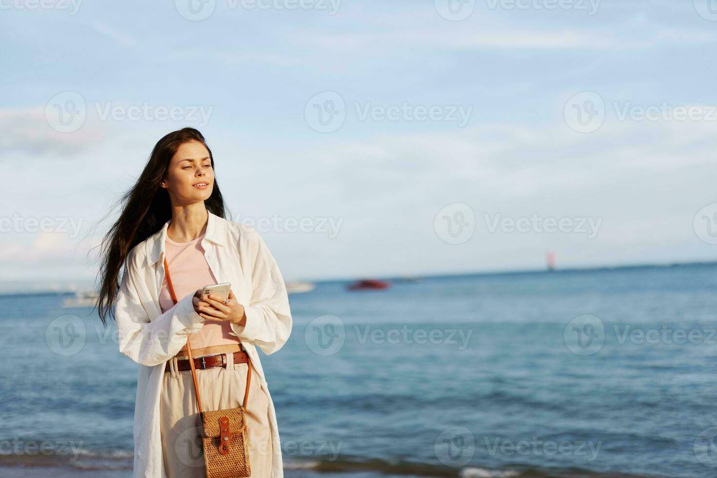 Lanza libre mujer con teléfono en mano en vacaciones caminando en el playa por el Oceano en bali, contento viaje y vacaciones, móvil comunicaciones, Internet en línea foto