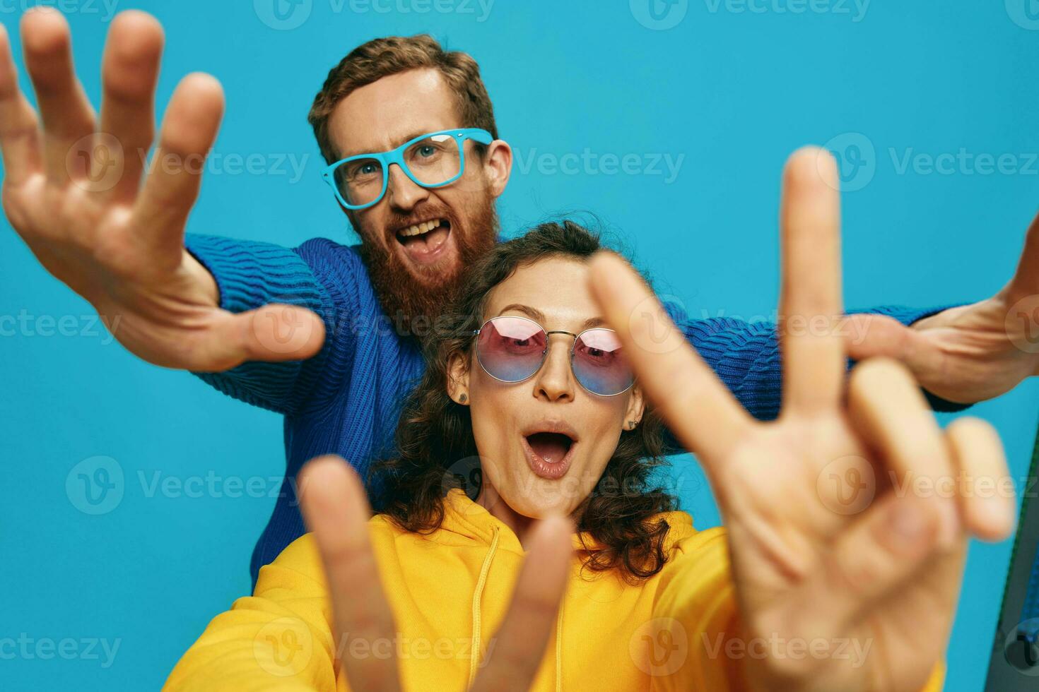 A woman and a man fun couple cranking and showing signs with their hands smiling cheerfully, on a blue background, The concept of a real relationship in a family. photo