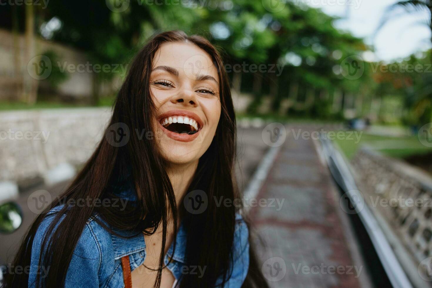 retrato de un mujer morena sonrisa con dientes caminando fuera de en contra un fondo de palma arboles en el zona tropical, verano vacaciones y al aire libre recreación, el despreocupado estilo de vida de un Lanza libre alumno. foto