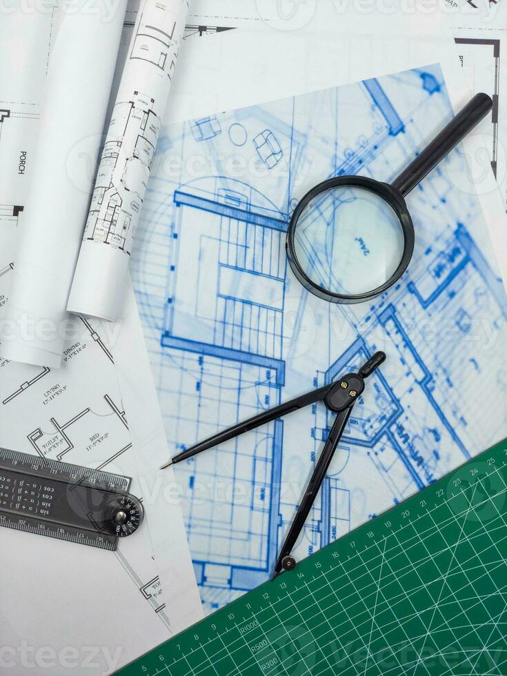 Architect engineer office desk. Blueprint plans and house model with ruler, compass, and magnifier glass photo