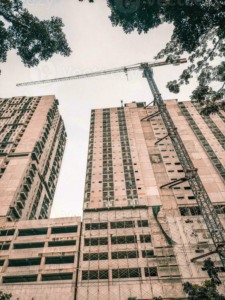 unfinished building construction and building cranes against clear blue sky background photo