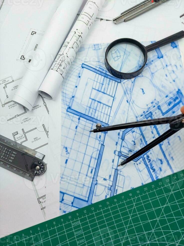 Architect engineer office desk. Blueprint plans and house model with ruler, compass, and magnifier glass photo