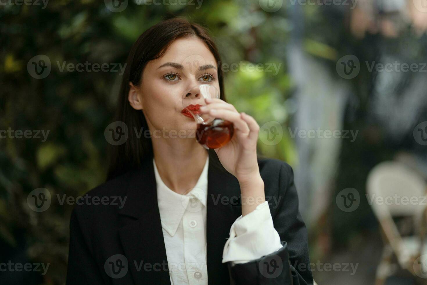 mujer con rojo labios sonrisa con dientes Bebiendo té en un café desde un turco vaso jarra en el calle, verano viajar, vacaciones en el ciudad foto