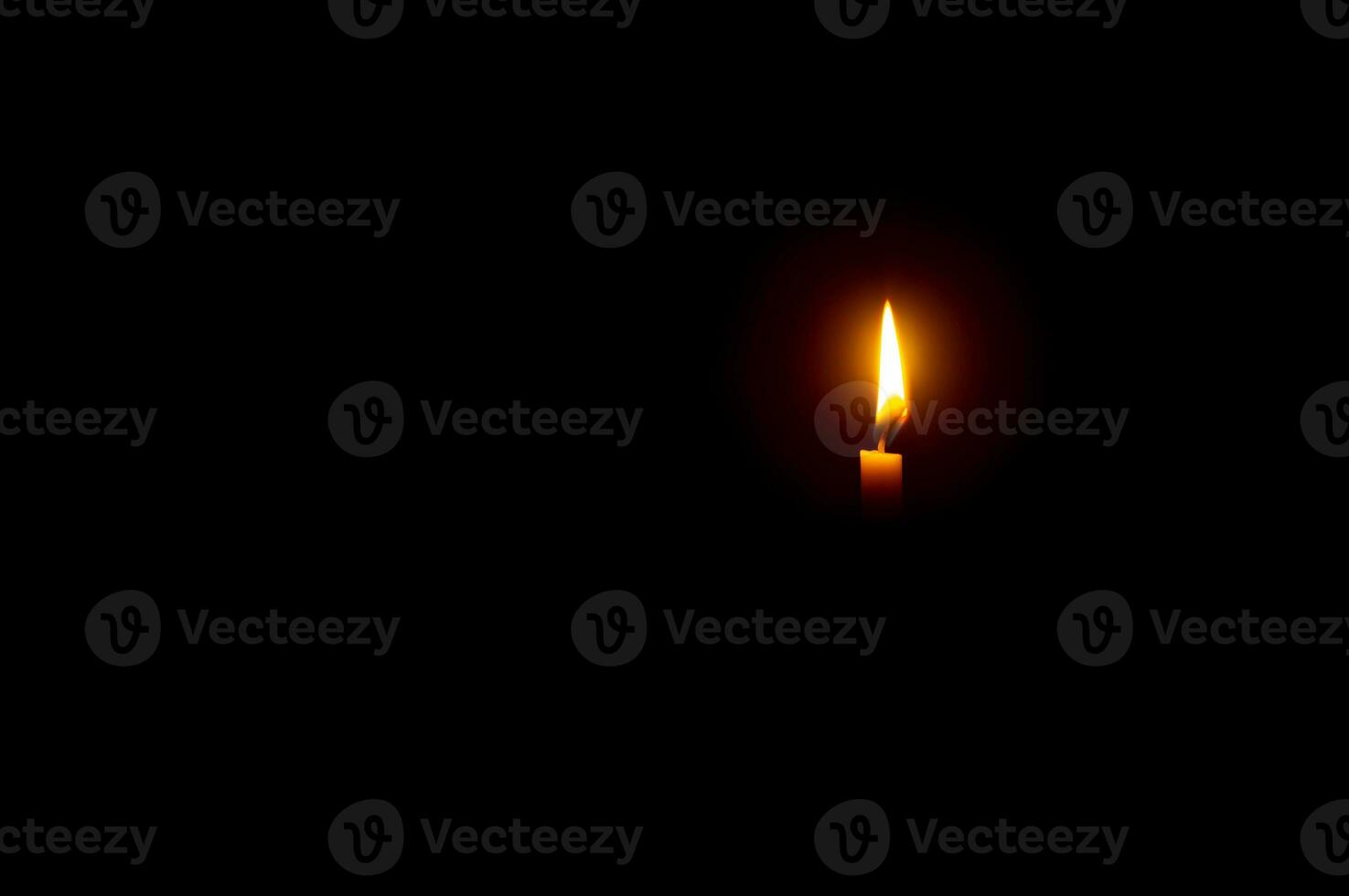 un soltero ardiente vela fuego o ligero brillante en un naranja vela en negro o oscuro antecedentes en mesa en Iglesia para Navidad, funeral o monumento Servicio con Copiar espacio. foto