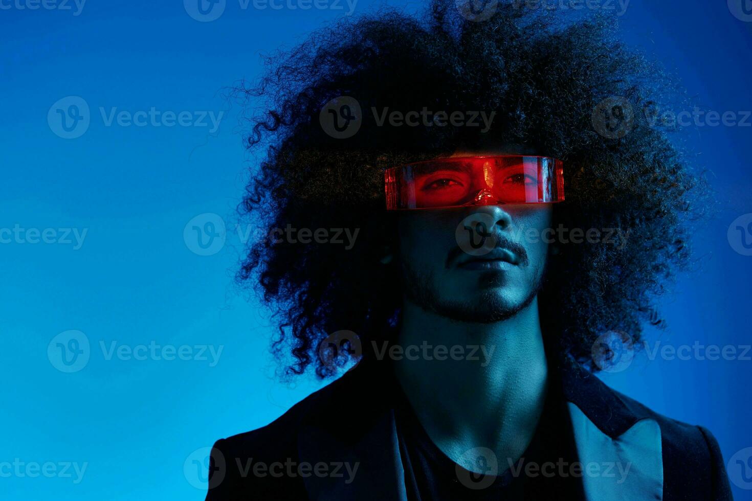 Fashion portrait of a man with curly hair on a blue background wearing red sunglasses, multinational, colored light, trendy, modern concept. photo