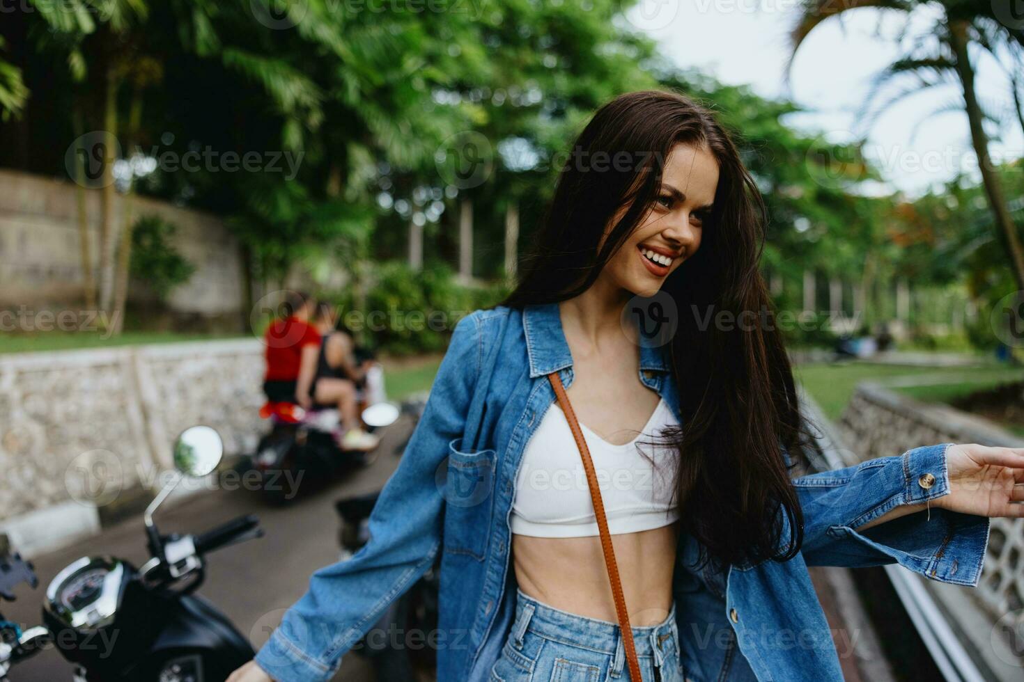 Portrait of woman brunette smile with teeth running down the street against backdrop palm trees in the tropics, summer vacations and outdoor recreation, the carefree lifestyle of a freelance student. photo