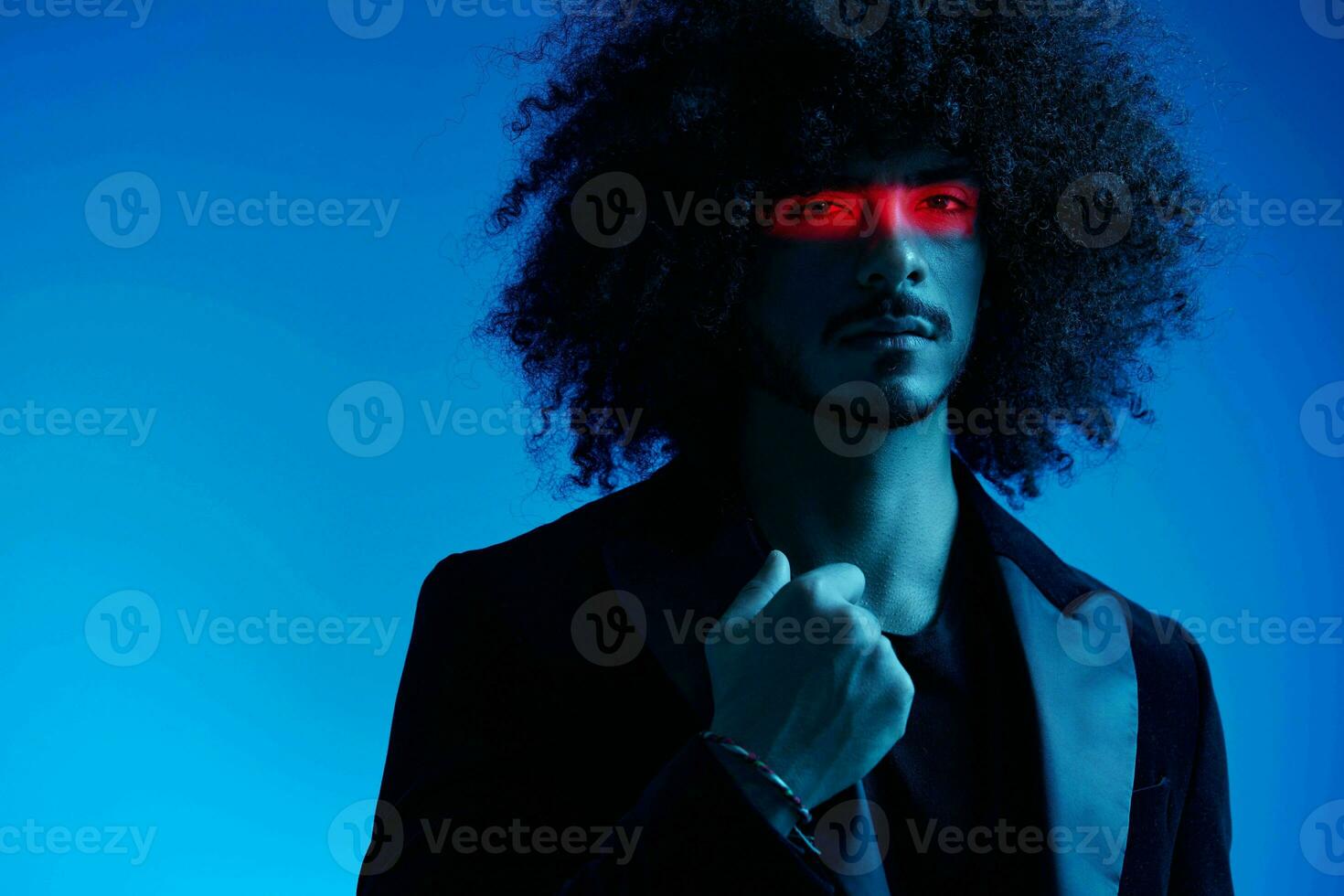 Fashion portrait of a man with curly hair on a blue background with a red stripe of light, multicolored light, trendy, modern concept. photo
