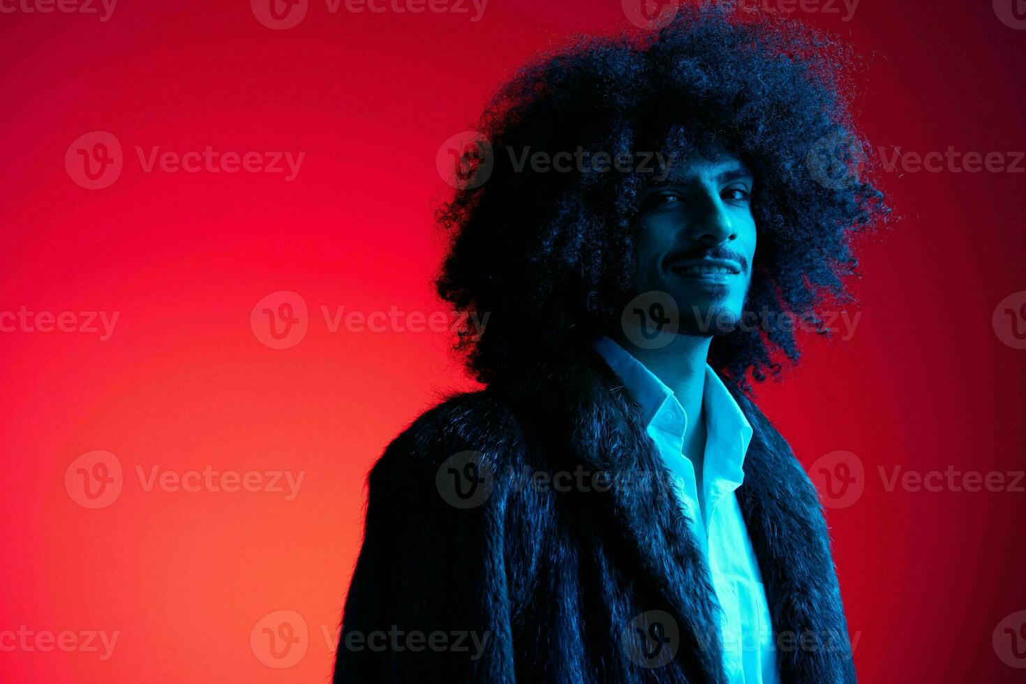 Fashion portrait of a man with curly hair on a red background, multinational, colored light, trendy, modern concept. photo