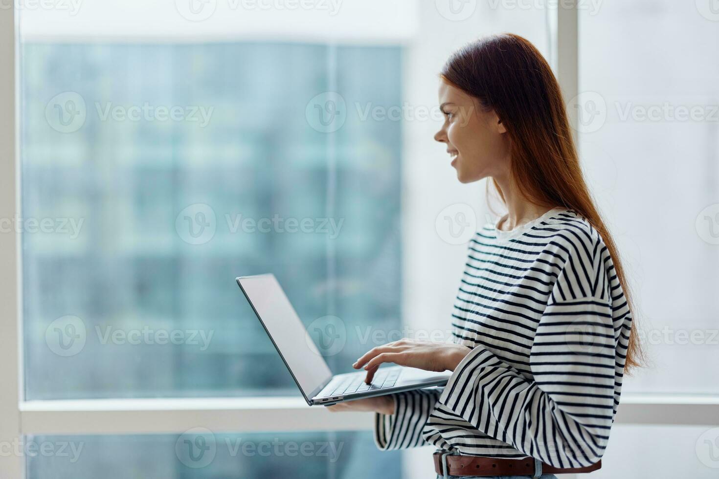 Business woman freelancer working in the city near a window and holding a laptop, working with technology online photo