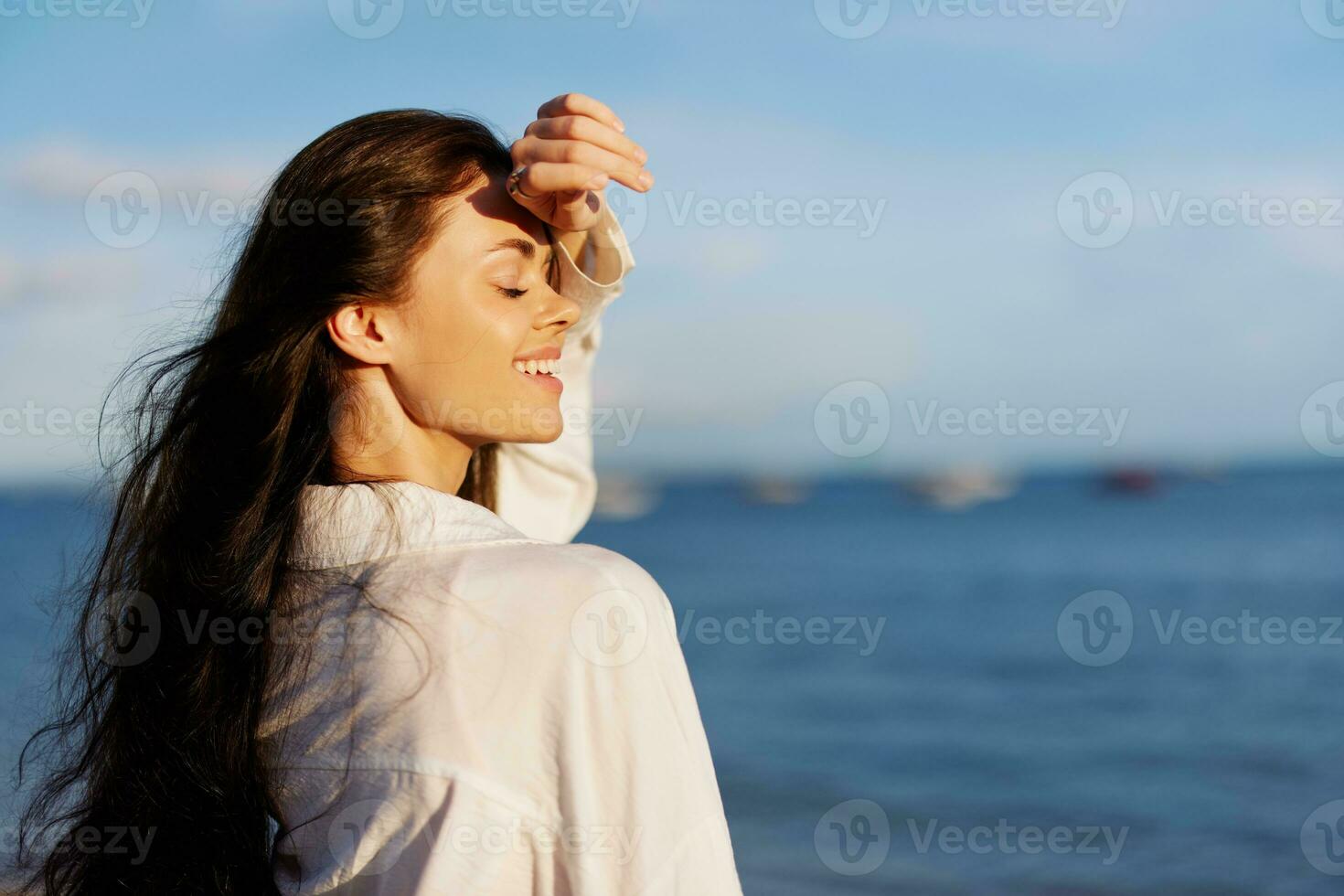 Woman beauty smile with teeth freedom on vacation walking on the beach by the ocean in Bali sunset, happy travel and vacation, sunset light, flying hair, skin and hair care concept in the sun photo