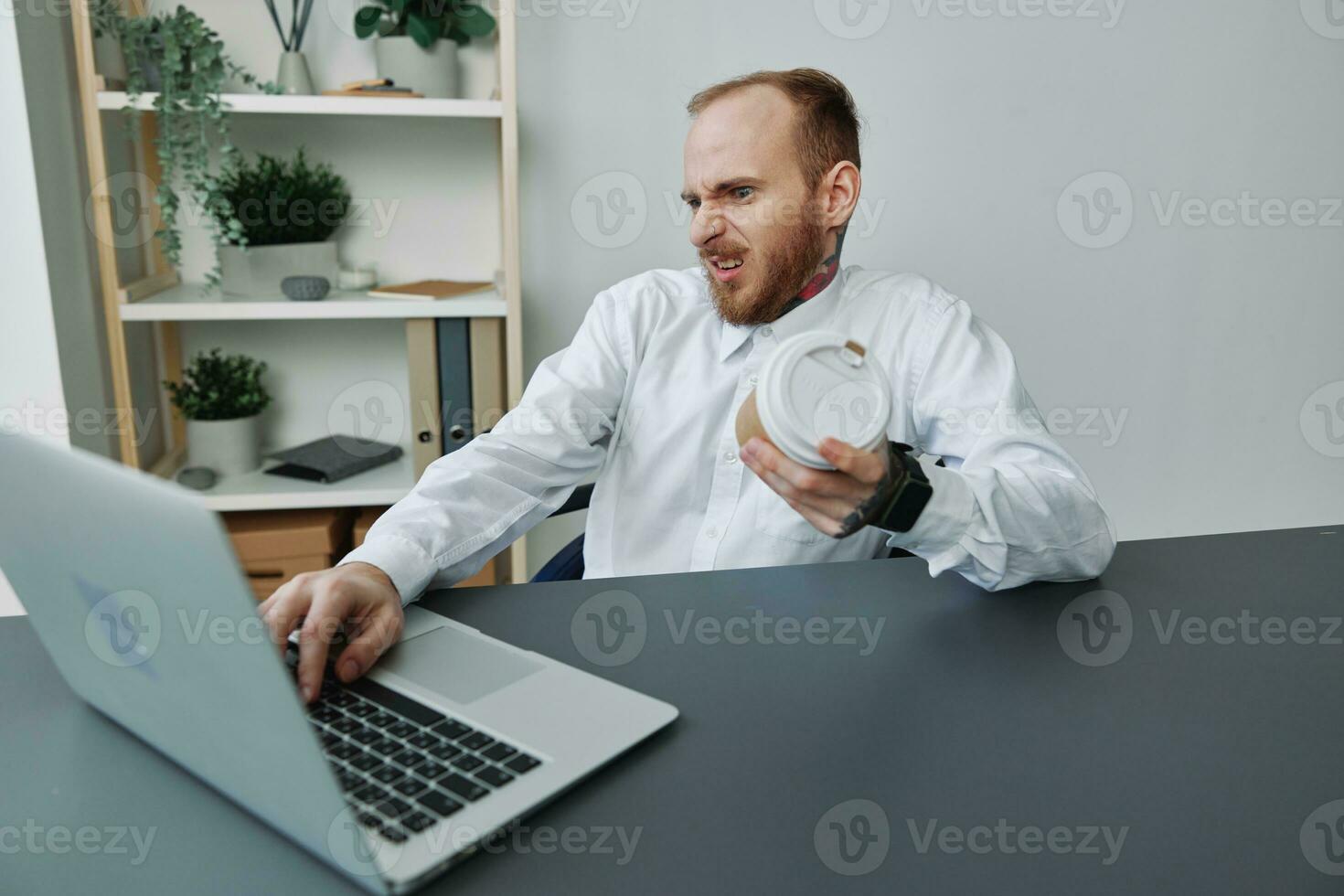 A man in a wheelchair, a businessman with tattoos in the office at a laptop, a coffee break, annoyance, the concept of working a person with disabilities, freedom from social frames photo
