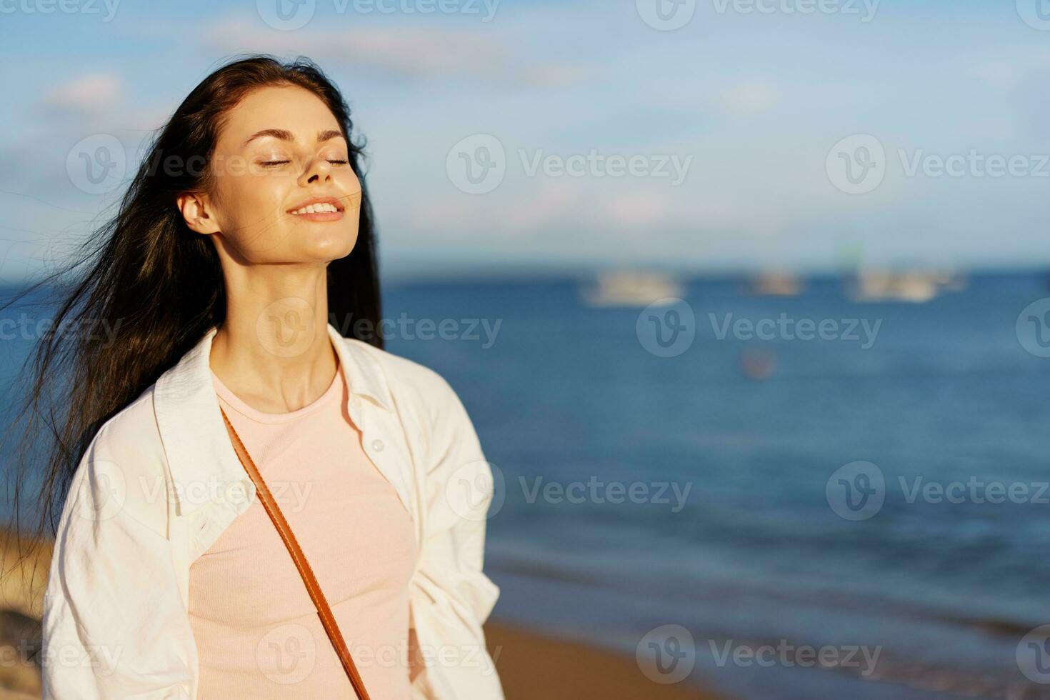 Woman beauty smile with teeth freedom on vacation walks along the beach near the ocean in Bali sunset, happy travel and vacation, sunset light, flying hair, enjoyment of relaxation and harmony photo