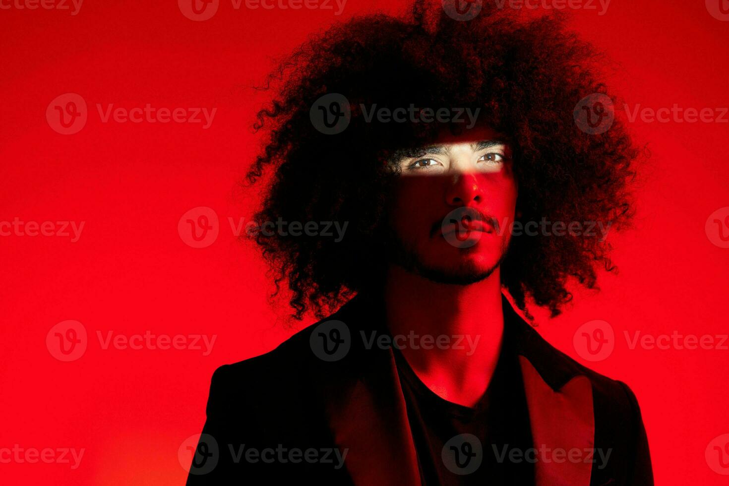 Fashion portrait of a man with curly hair on a red background, multinational, colored light, trendy, modern concept. photo