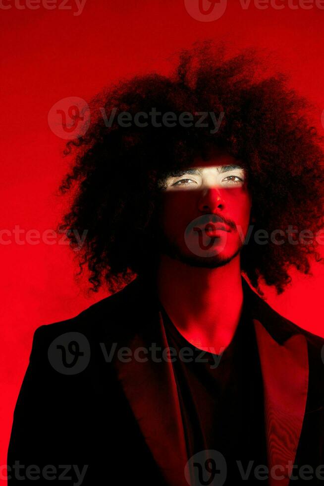 Fashion portrait of a man with curly hair on a red background, multinational, colored light, trendy, modern concept. photo