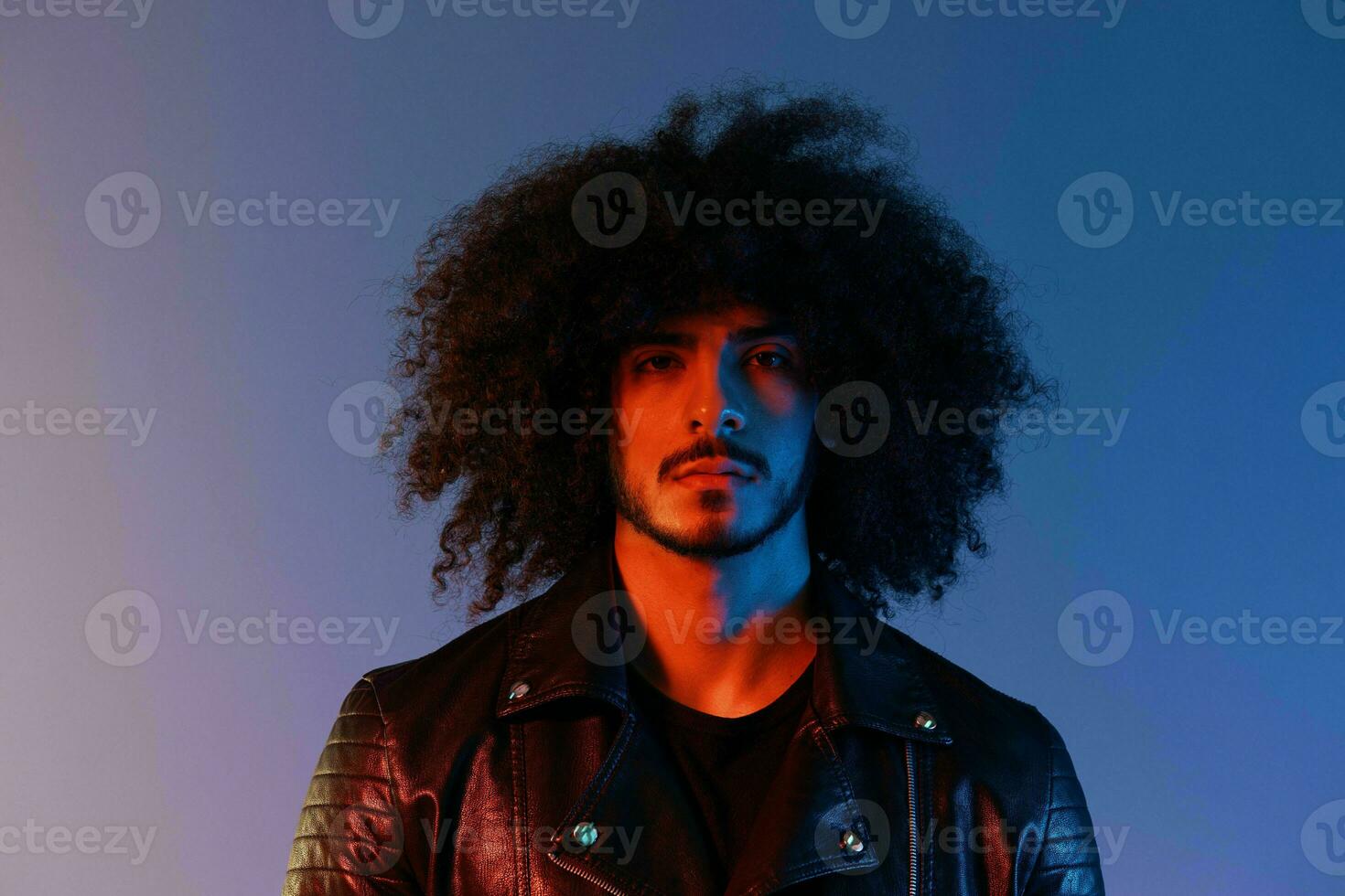 Portrait of a stylish man with curly hair in smoke on a blue background multinational, color light, trendy, modern concept. photo
