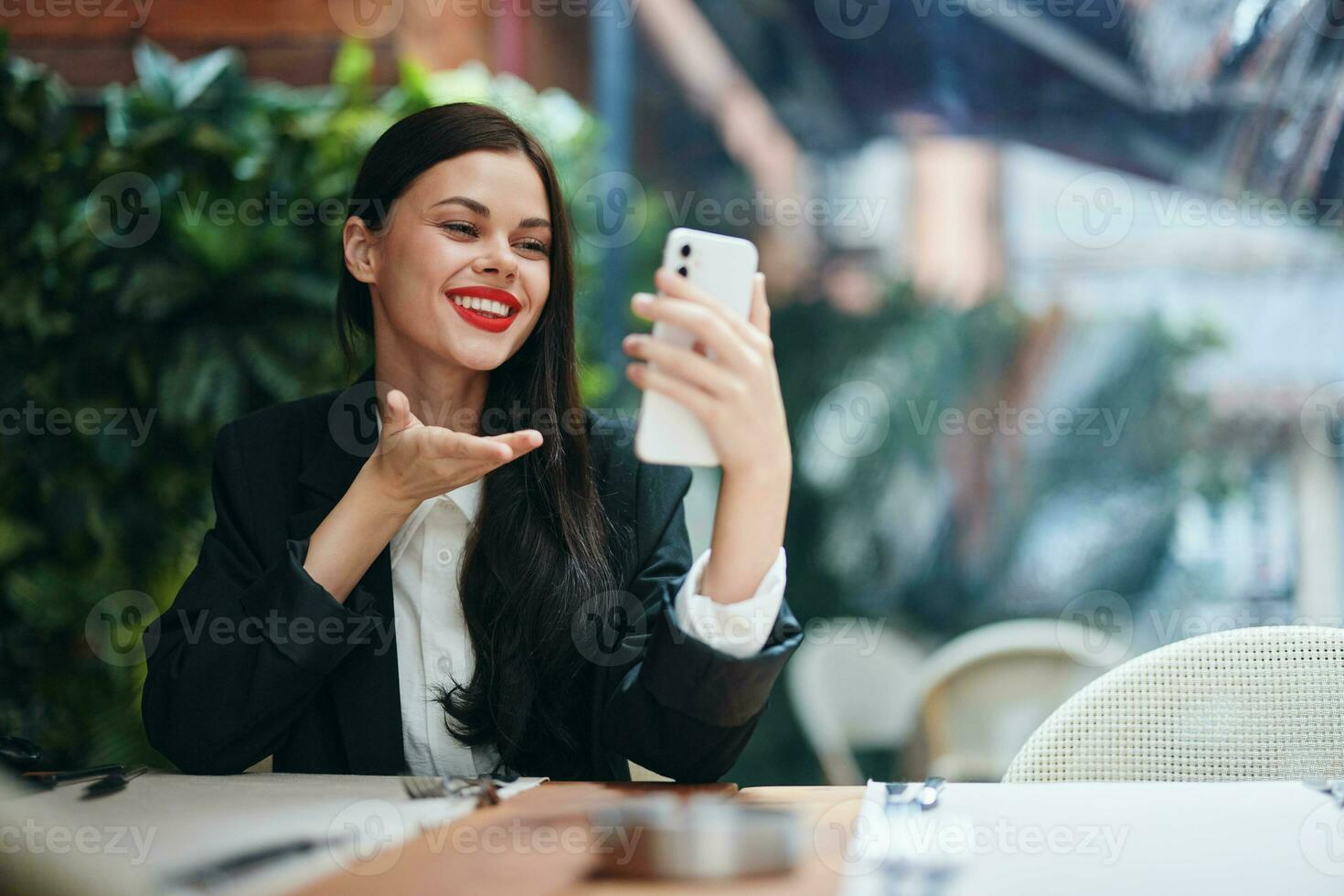 Stylish woman blogger tourist sits in a cafe with a phone in her hands reads a message, mobile communication and internet on a journey, video call, freelance work online, smile with teeth photo