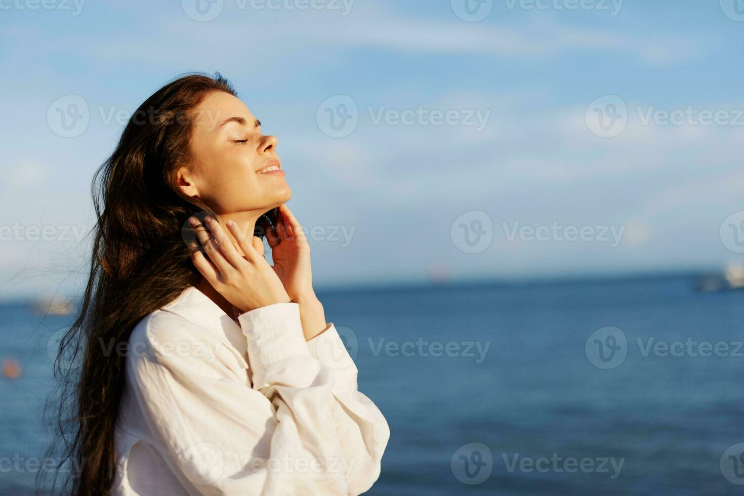 Woman beauty smile with teeth freedom on vacation walking on the beach by the ocean in Bali sunset, happy travel and vacation, sunset light, flying hair, skin and hair care concept in the sun photo