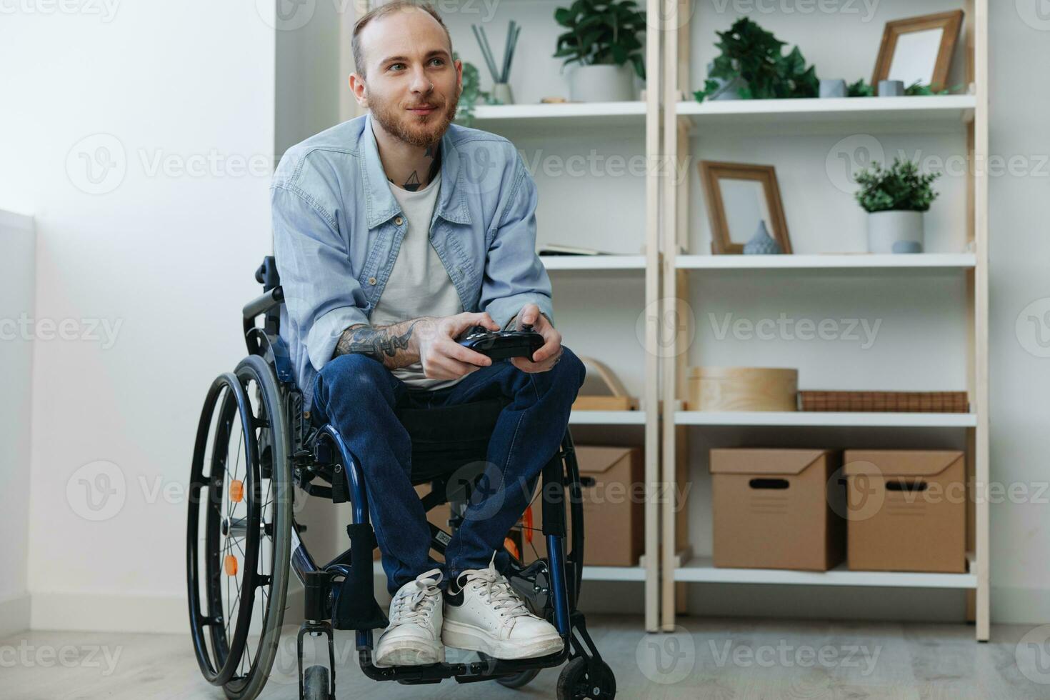 A man in a wheelchair gamer plays games with a joystick in his hands at home, surprise open mouth, copy space, with tattoos on his hands, health concept man with disabilities, real person photo