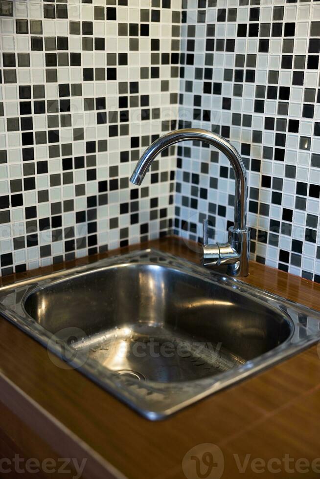 Clean sink with pouring water in the kitchen, metal faucet and sink in an old home interior. photo