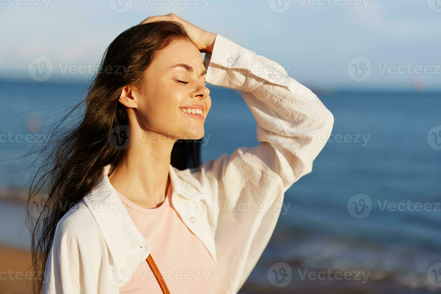 Woman portrait smile with teeth freedom vacation walking on the beach by the ocean in Bali sunset, happy journey and relaxation, sunset light, flying hair, the concept of change and emotional health photo