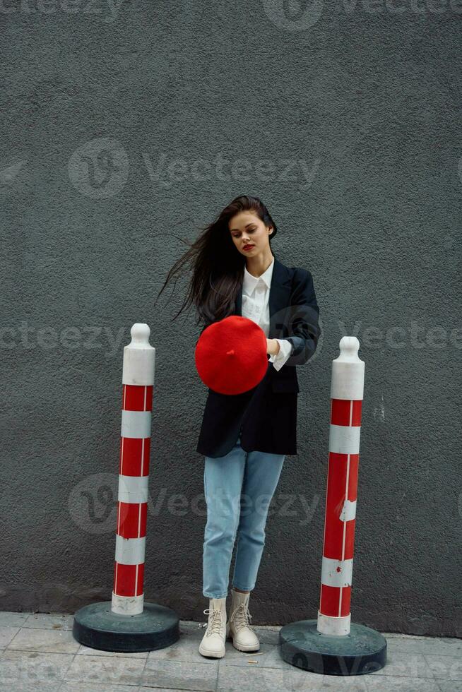 Fashion woman standing on the street in front of the city and road works tourist in stylish clothes with red lips and red beret, travel, cinematic color, retro vintage style, urban fashion. photo
