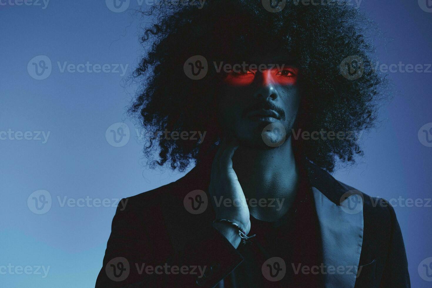 Fashion portrait of a man with curly hair on a blue background with a red stripe of light, multicolored light, trendy, modern concept. photo