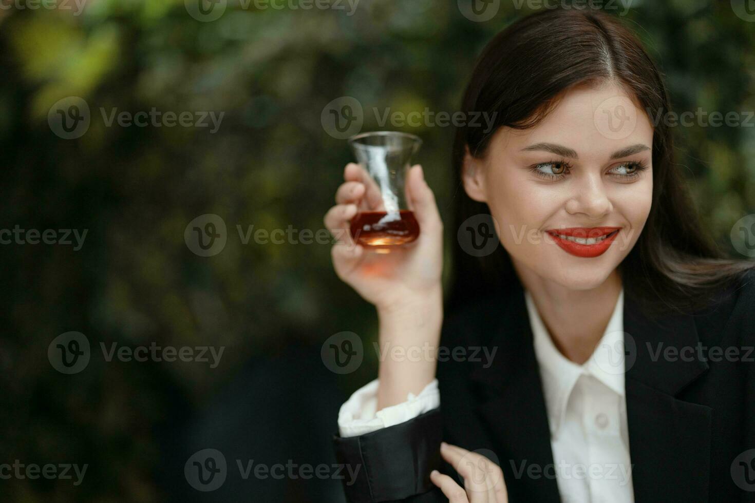 Woman smile with teeth drinking tea in a cafe from a Turkish glass mug on the street photo