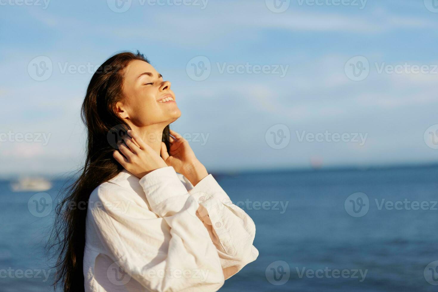 Woman beauty smile with teeth freedom on vacation walking on the beach by the ocean in Bali sunset, happy travel and vacation, sunset light, flying hair, skin and hair care concept in the sun photo