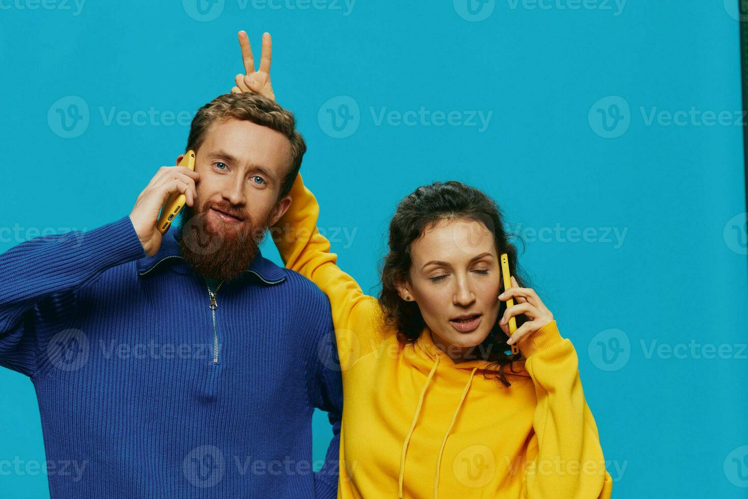Woman and man cheerful couple with phones in their hands crooked smile cheerful, on blue background. The concept of real family relationships, talking on the phone, work online. photo