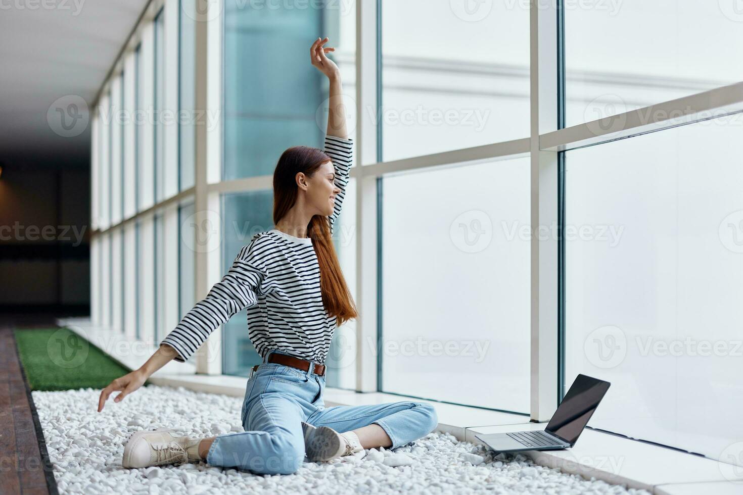 A woman freelancer sits in the office lobby by the big windows with a laptop online via the Internet, freelance work anywhere in the world photo