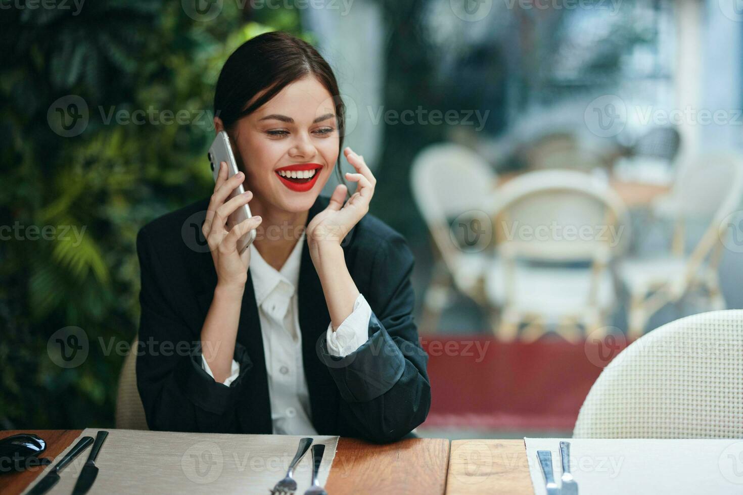 woman blogger tourist sits in a cafe at a table with a phone in her hands talking on the phone, mobile communications and the Internet on a spring trip, video call, freelance work online, smile photo