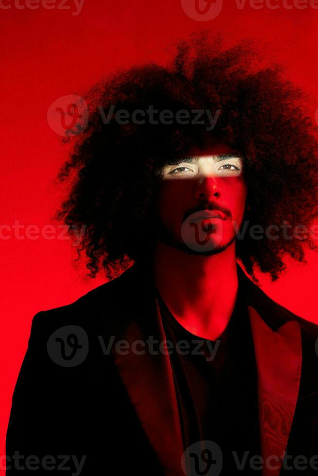 Fashion portrait of a man with curly hair on a red background, multinational, colored light, trendy, modern concept. photo