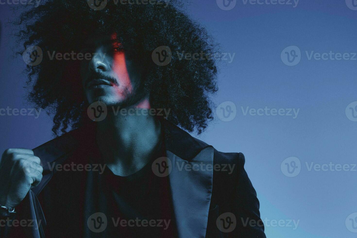 Fashion portrait of a man with curly hair on a blue background, multinational, colored light, trendy, modern concept. photo