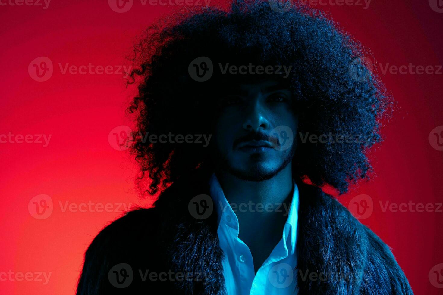 Fashion portrait of a man with curly hair on a red background, multinational, colored light, trendy, modern concept. photo